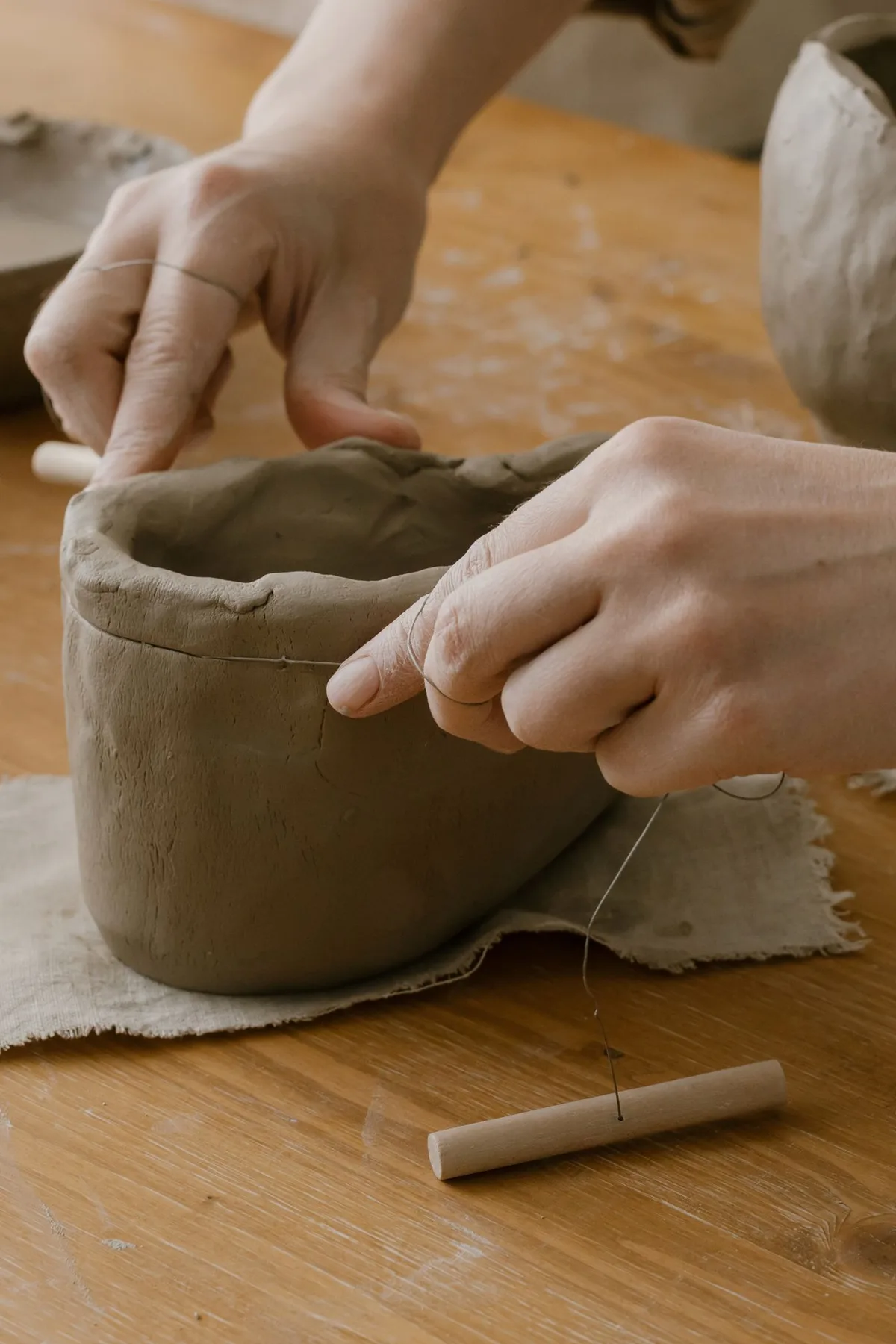 A maker carefully shaping a handmade clay vessel